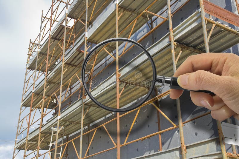 کارکنان با ابزار دقیق در حال انجام بازرسی کیفیت نمای ساختمان روی سکوهای ایمنی
